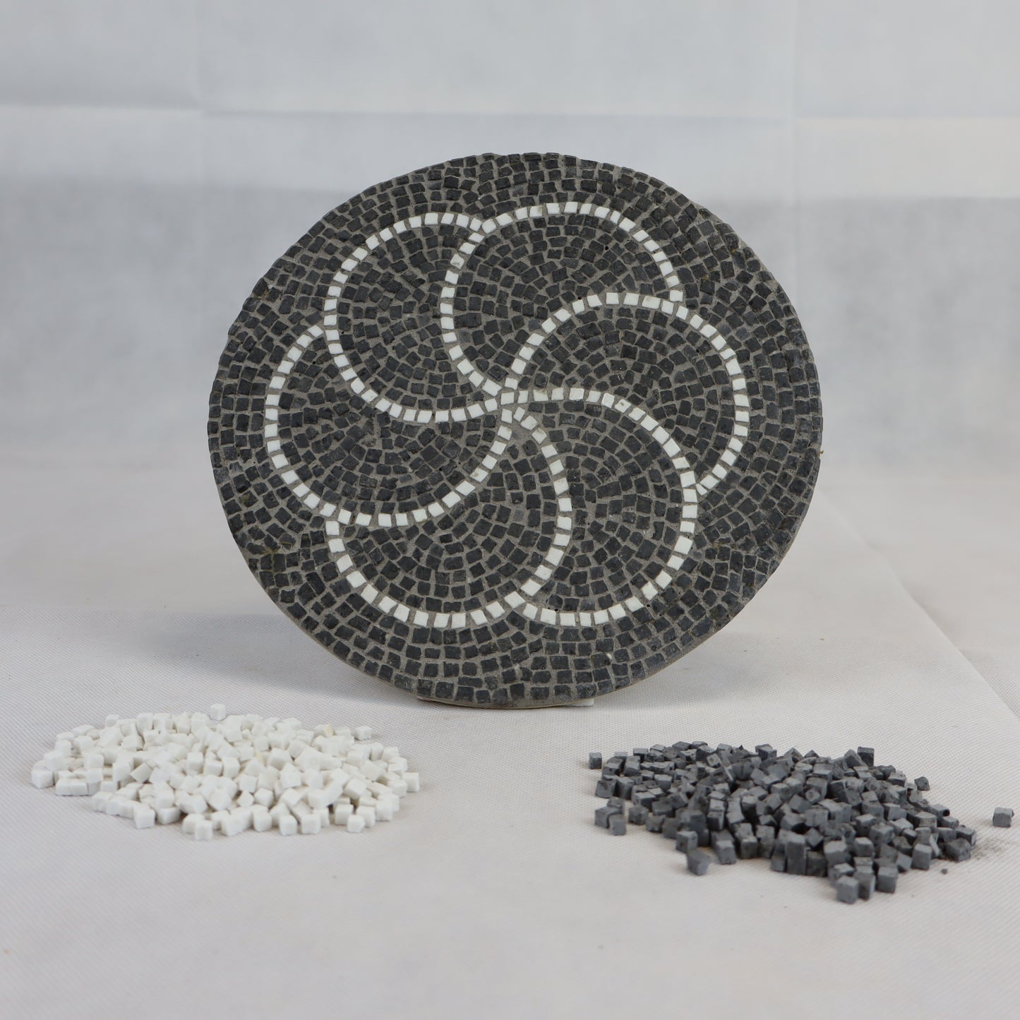 Composizione circolare con sanpietrini di colore grigio scuro e bianco dimensioni 4x4 mm.