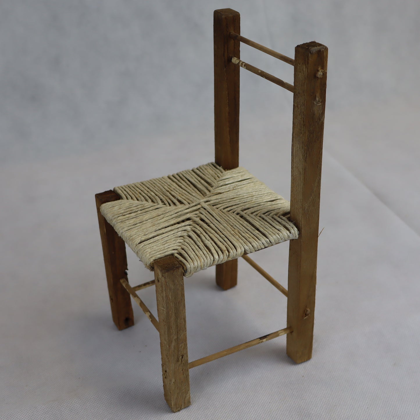 Sedia rustica in miniatura realizzata in legno grezzo, con seduta intrecciata in paglia naturale.
Misura circa 24 cm di altezza e 11 cm di larghezza, ed è ideale per arredare ambientazioni in scala ispirate alla vita contadina, scene rurali o presepi artigianali.