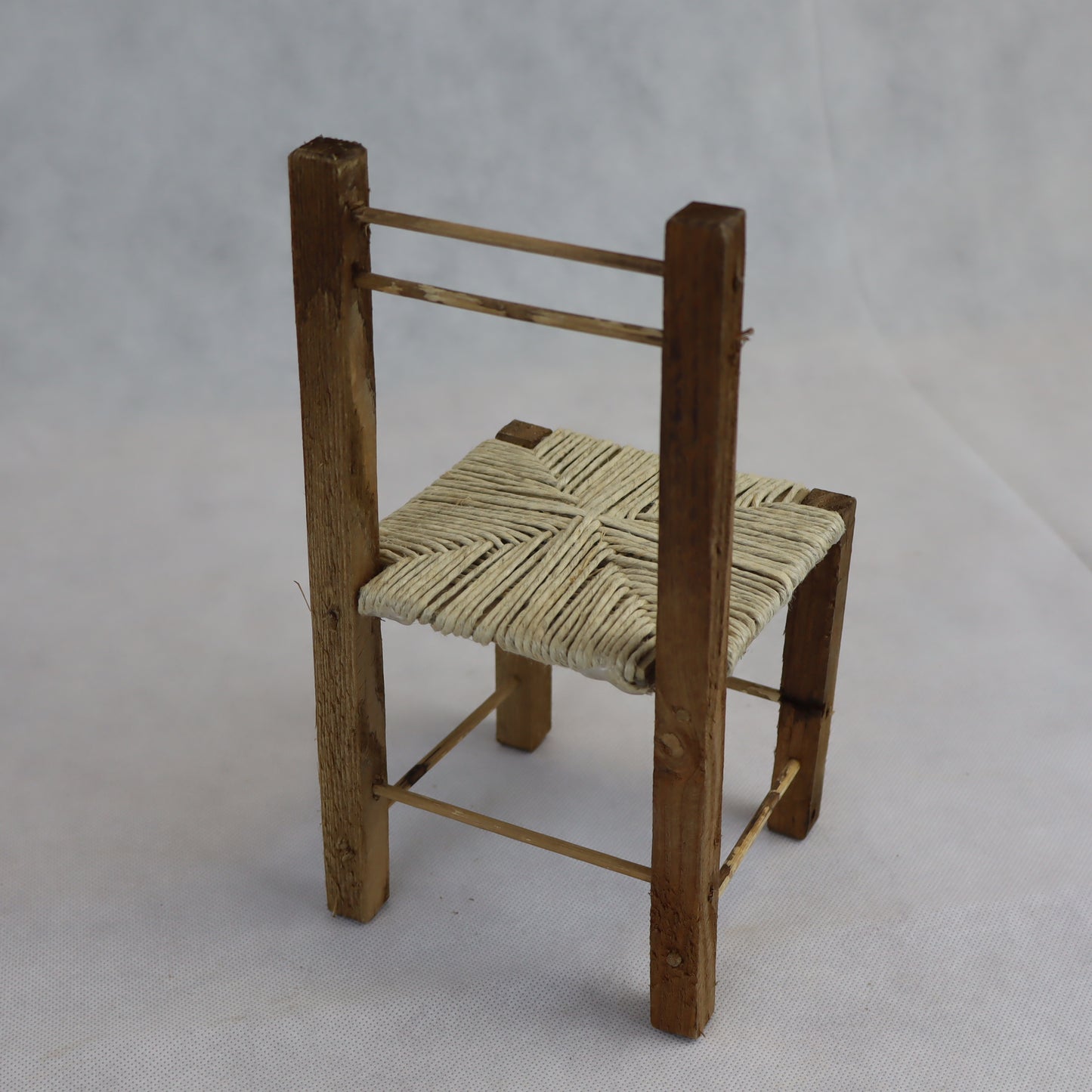 Sedia rustica in miniatura realizzata in legno grezzo, con seduta intrecciata in paglia naturale.
Misura circa 24 cm di altezza e 11 cm di larghezza, ed è ideale per arredare ambientazioni in scala ispirate alla vita contadina, scene rurali o presepi artigianali.
