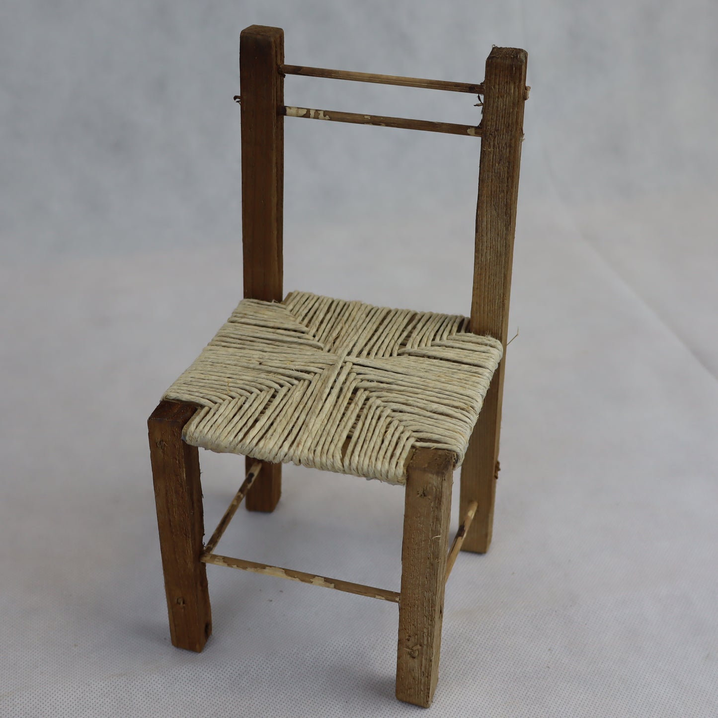 Sedia rustica in miniatura realizzata in legno grezzo, con seduta intrecciata in paglia naturale.
Misura circa 24 cm di altezza e 11 cm di larghezza, ed è ideale per arredare ambientazioni in scala ispirate alla vita contadina, scene rurali o presepi artigianali.