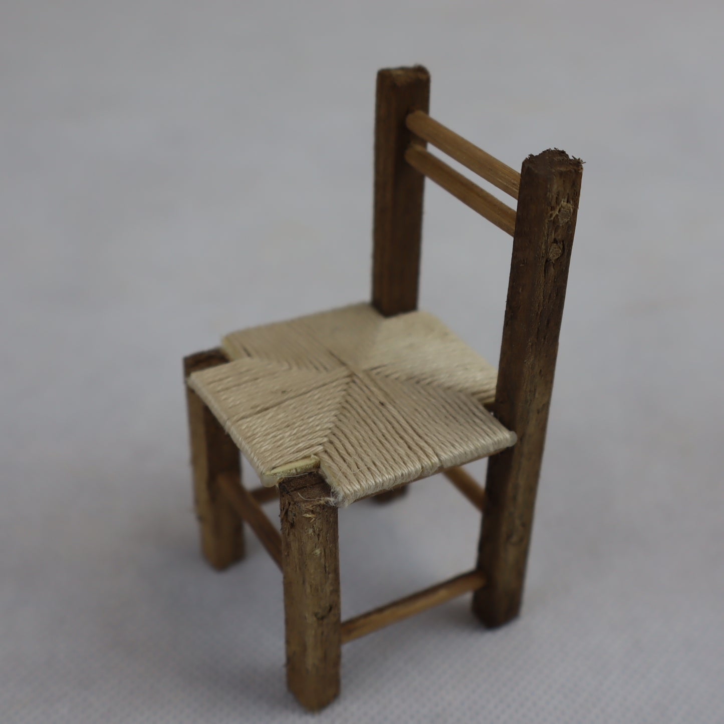 Miniatura artigianale di sedia rustica, realizzata in legno grezzo con seduta intrecciata in paglia naturale.
Le dimensioni contenute (8 cm di altezza x 4 cm di larghezza) la rendono ideale per ricreare ambientazioni rurali, scene contadine o interni tradizionali in presepi, diorami e plastici in scala ridotta.