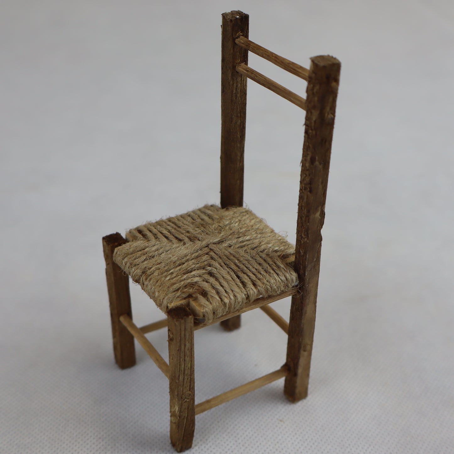 Sedia in miniatura realizzata in legno grezzo con seduta intrecciata in paglia naturale.
Le sue dimensioni contenute (circa 12 cm di altezza e 5 cm di larghezza) la rendono perfetta per arredare scene rustiche in presepi, diorami, plastici architettonici o ambientazioni ispirate alla vita contadina.