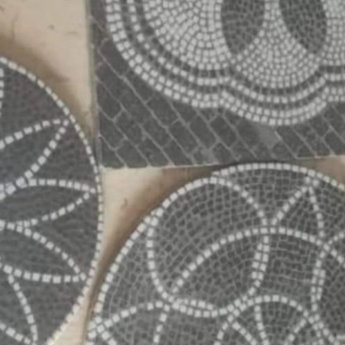 Tre piastrelle in mosaico artistico con motivi geometrici e floreali; evidenziato il modello circolare in basso a destra con intrecci curvilinei bianchi su fondo grigio scuro.