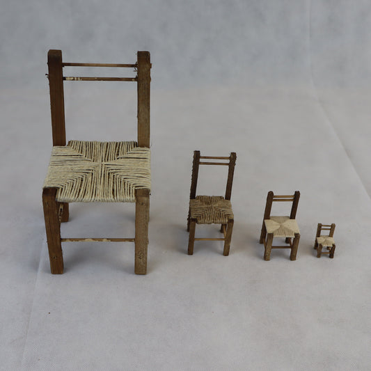 Quattro sedie rustiche in miniatura realizzate in legno grezzo, con seduta intrecciata in paglia naturale.
