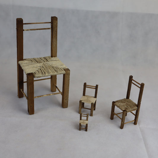 Quattro sedie rustiche in miniatura realizzate in legno grezzo, con seduta intrecciata in paglia naturale.
