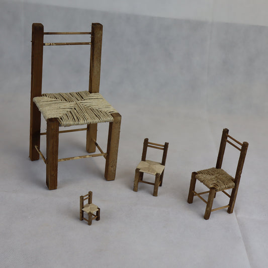 Quattro sedie rustiche in miniatura realizzate in legno grezzo, con seduta intrecciata in paglia naturale.

