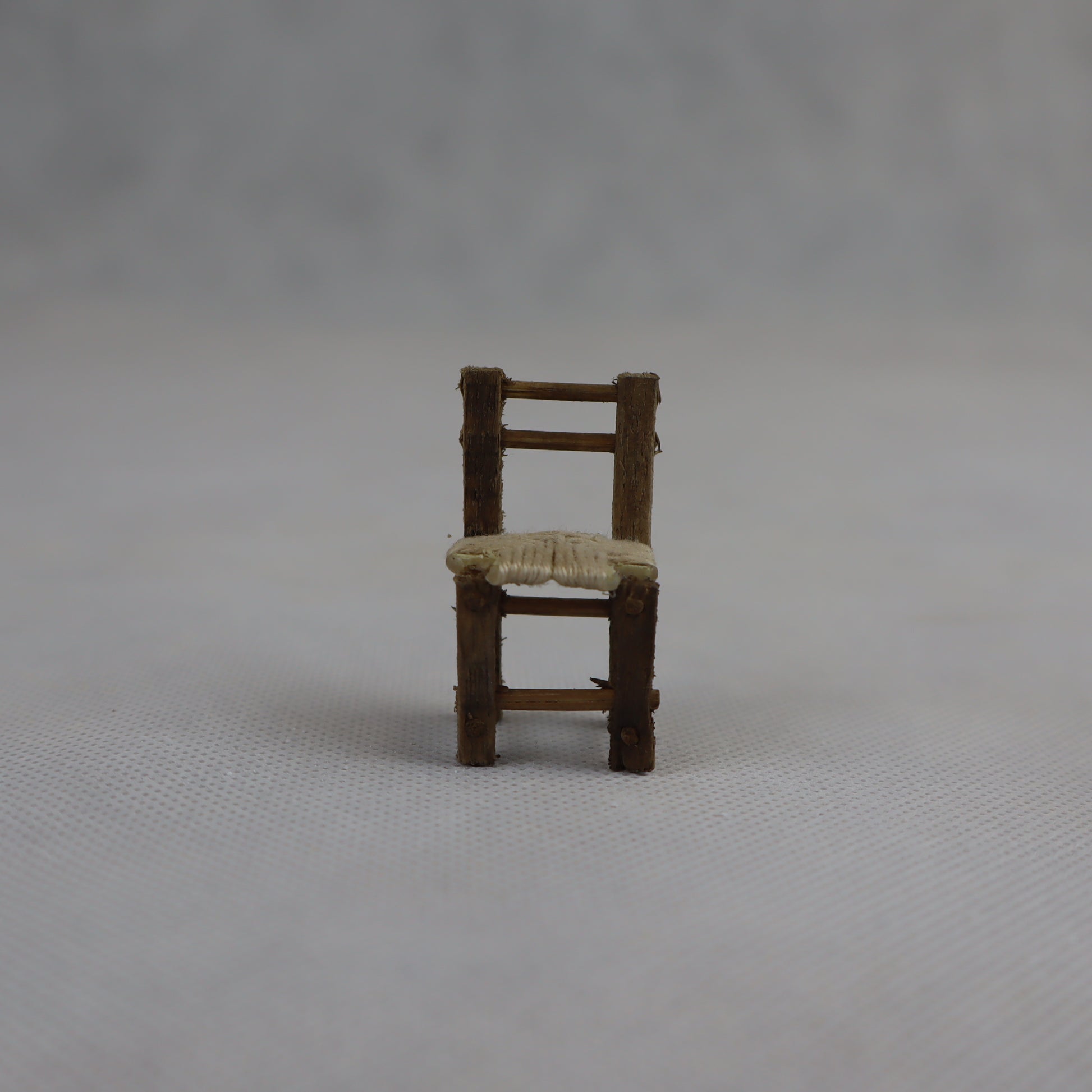 Piccola sedia in miniatura realizzata a mano in legno grezzo, con seduta intrecciata in paglia naturale.
Con un'altezza di circa 4 cm e una larghezza di 2 cm, è ideale per arricchire ambientazioni in scala ridotta come presepi artigianali, diorami rurali e scenografie tradizionali.
