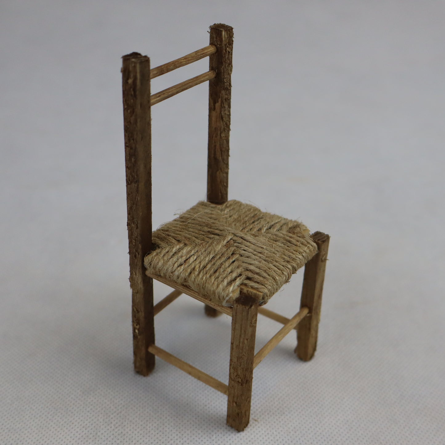 Sedia in miniatura realizzata in legno grezzo con seduta intrecciata in paglia naturale.
Le sue dimensioni contenute (circa 12 cm di altezza e 5 cm di larghezza) la rendono perfetta per arredare scene rustiche in presepi, diorami, plastici architettonici o ambientazioni ispirate alla vita contadina.