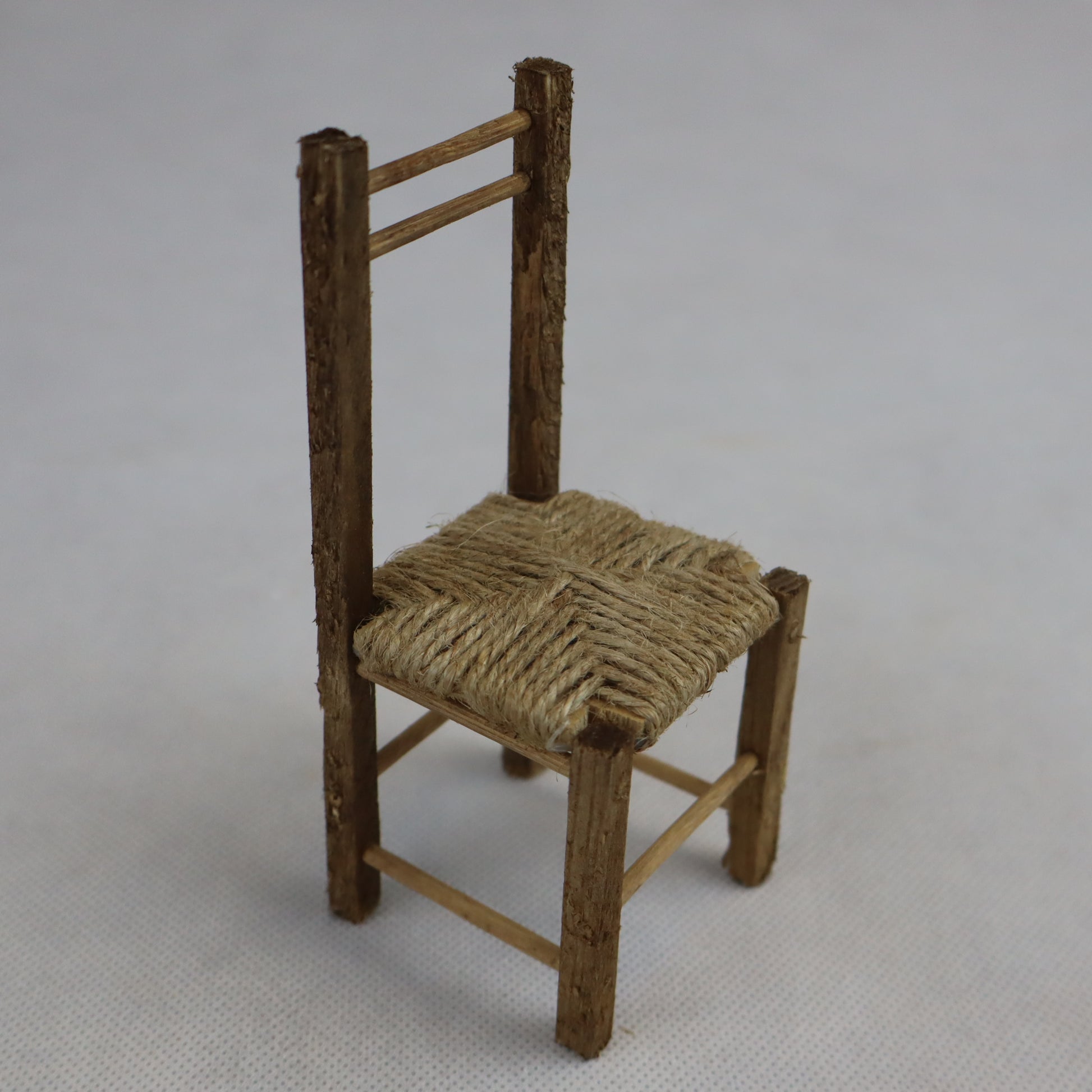 Sedia in miniatura realizzata in legno grezzo con seduta intrecciata in paglia naturale.
Le sue dimensioni contenute (circa 12 cm di altezza e 5 cm di larghezza) la rendono perfetta per arredare scene rustiche in presepi, diorami, plastici architettonici o ambientazioni ispirate alla vita contadina.