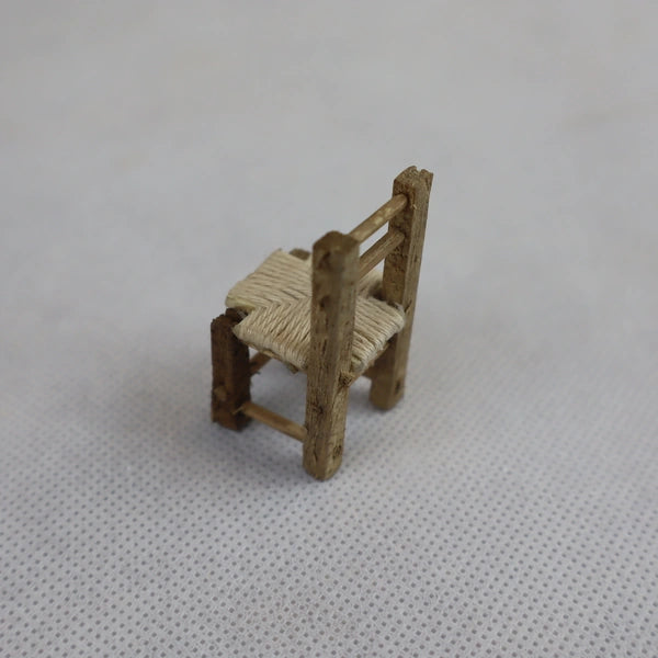 Dettaglio sedia rustica in miniatura in legno grezzo e paglia naturale